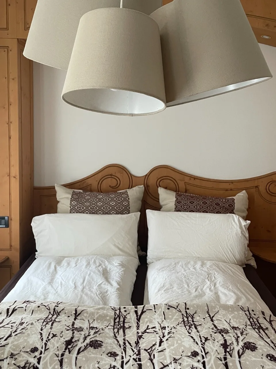 The room at Rifugio Cereda: wooden headboard, linen lampshades