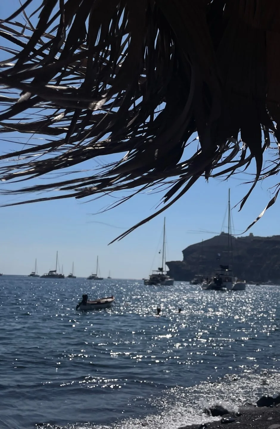 The sea from under a straw parasol, boats in the bay