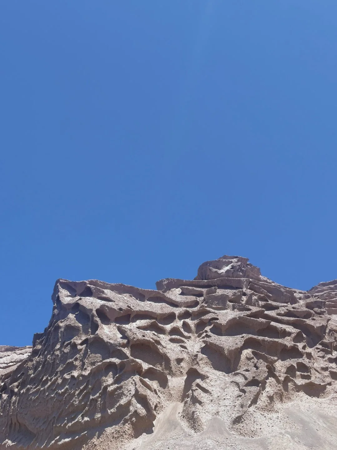 Pale volcanic cliffs against a deep blue sky